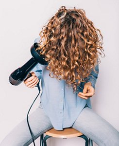 Woman with curly hair drying her hair with a diffuser